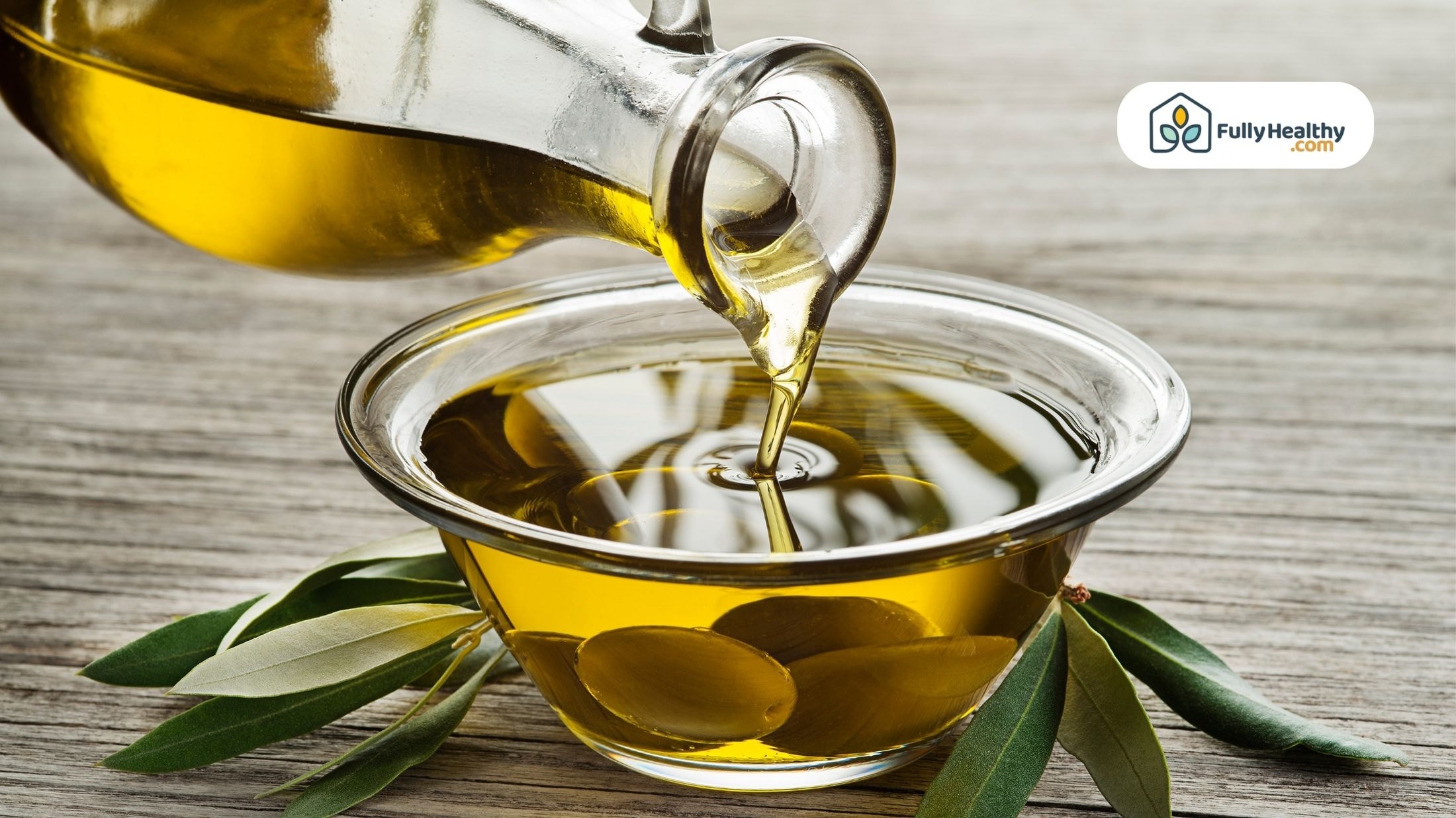 Pouring extra virgin olive oil into a glass bowl with olives