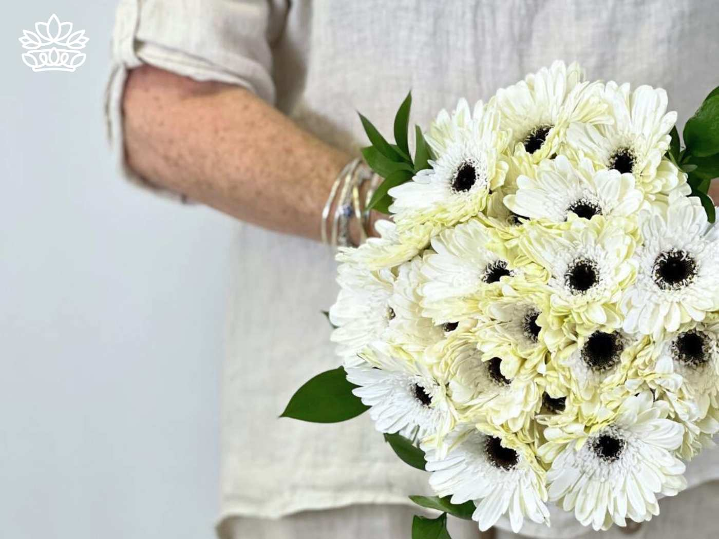 Close-up of a woman holding a bouquet of fresh white gerberas with dark centers, symbolizing purity and innocence. Gerberas Collection. Delivered with Heart. Fabulous Flowers and Gifts.