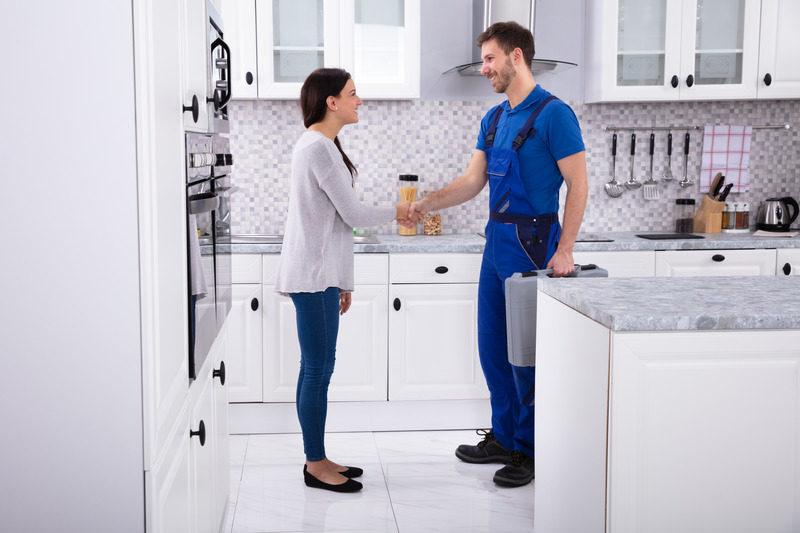 Installateur in Arbeitskleidung mit Kundin