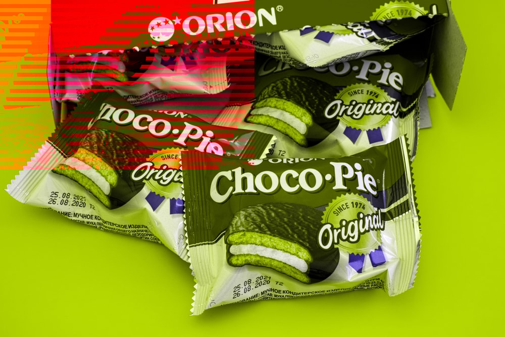 Tambov, Russian Federation - October 30, 2020 Orion Choco-Pie snack cakes spills out of the box. Yellow background.