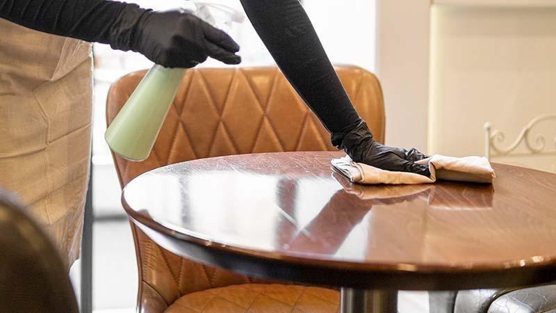 Cafe worker cleaning table with microfiber
