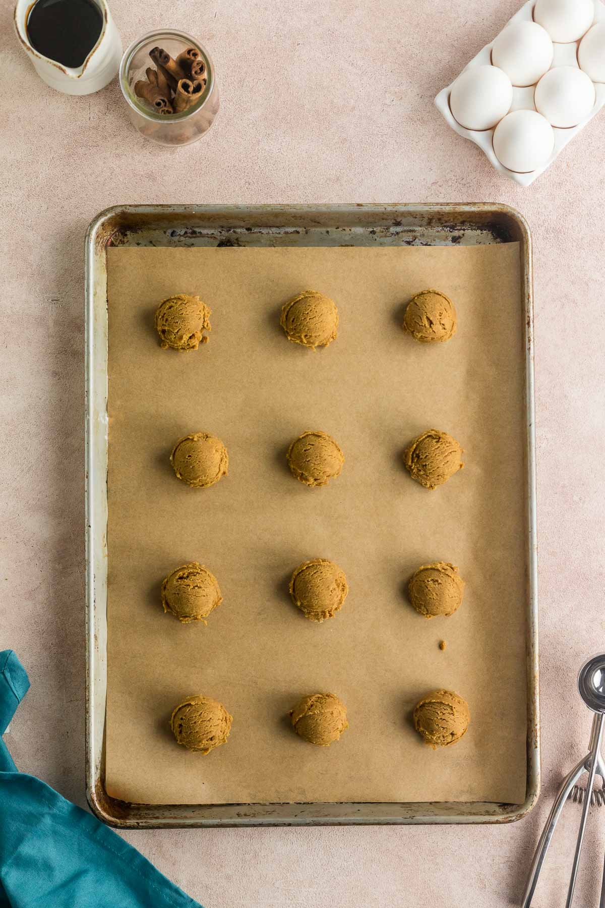 scooped molasses cookies on a parchment paper lined baking sheet