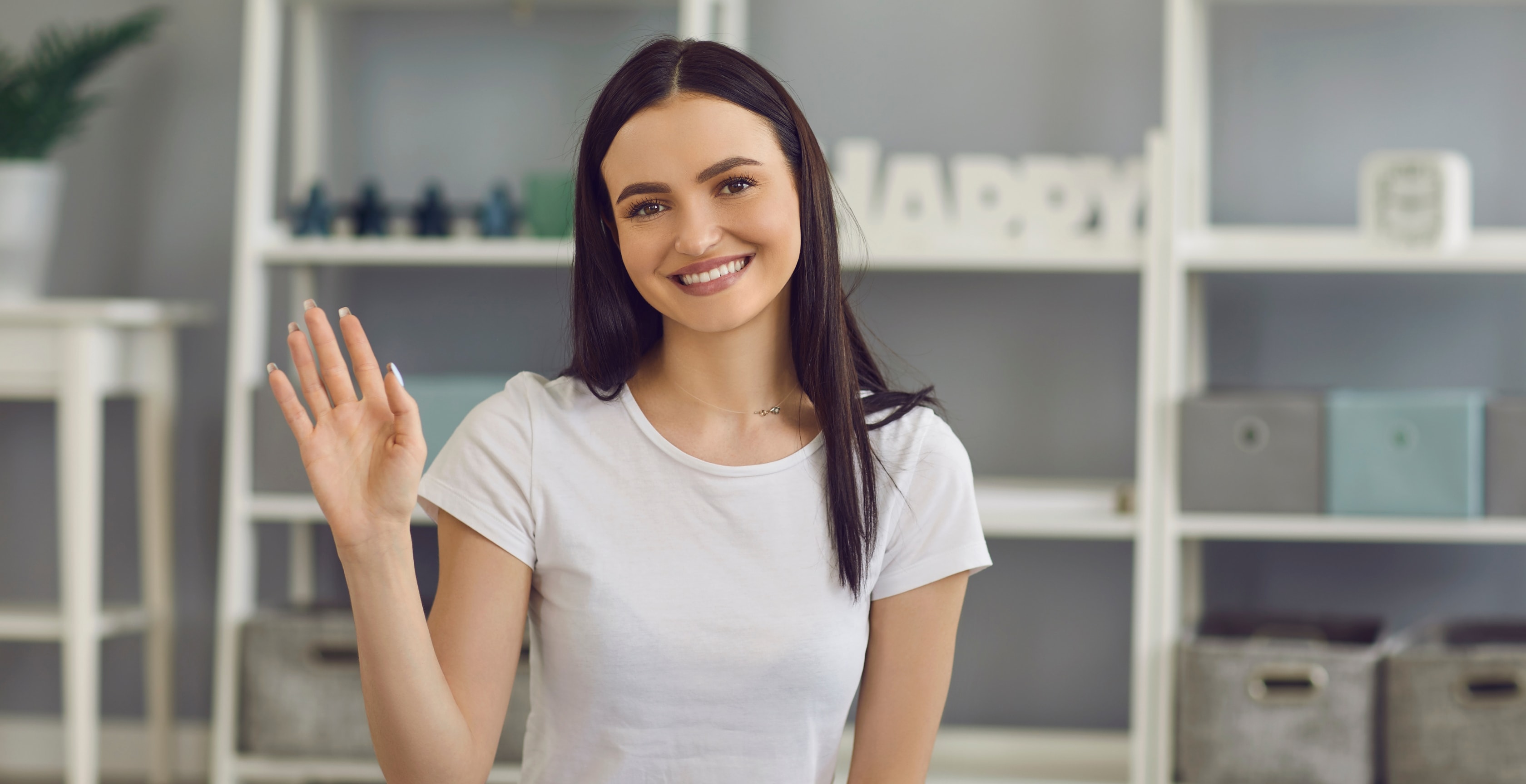 Smiling woman waving in her home office, exploring the home office deduction calculator for tax benefits.