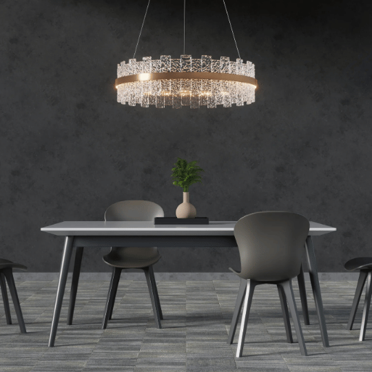 A modern dining area featuring a sleek rectangular table and gray chairs, illuminated by an elegant crystal chandelier design with gold accents hanging above, against a dark textured wall.