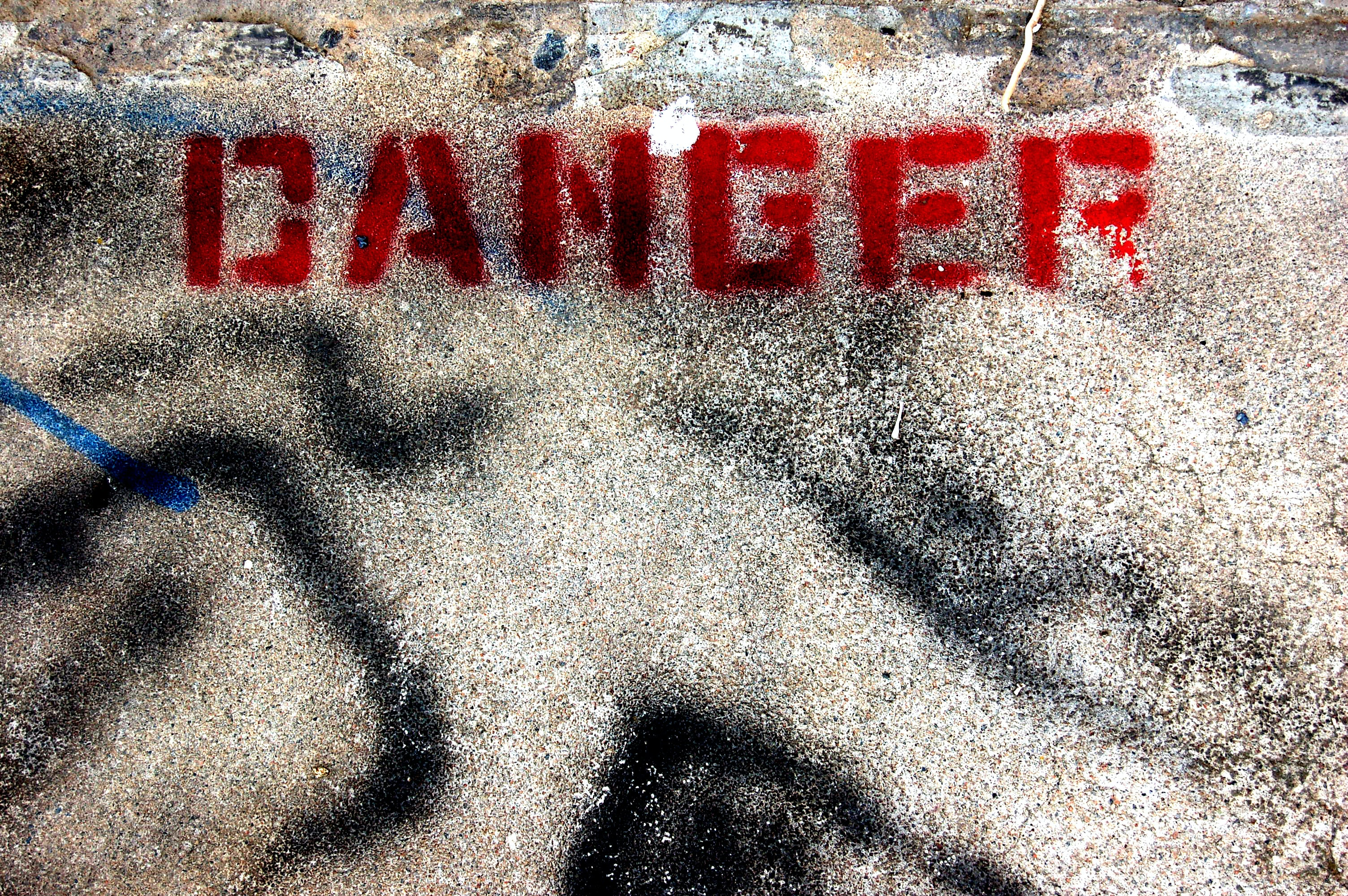 A spray painted on a road that says "Danger".