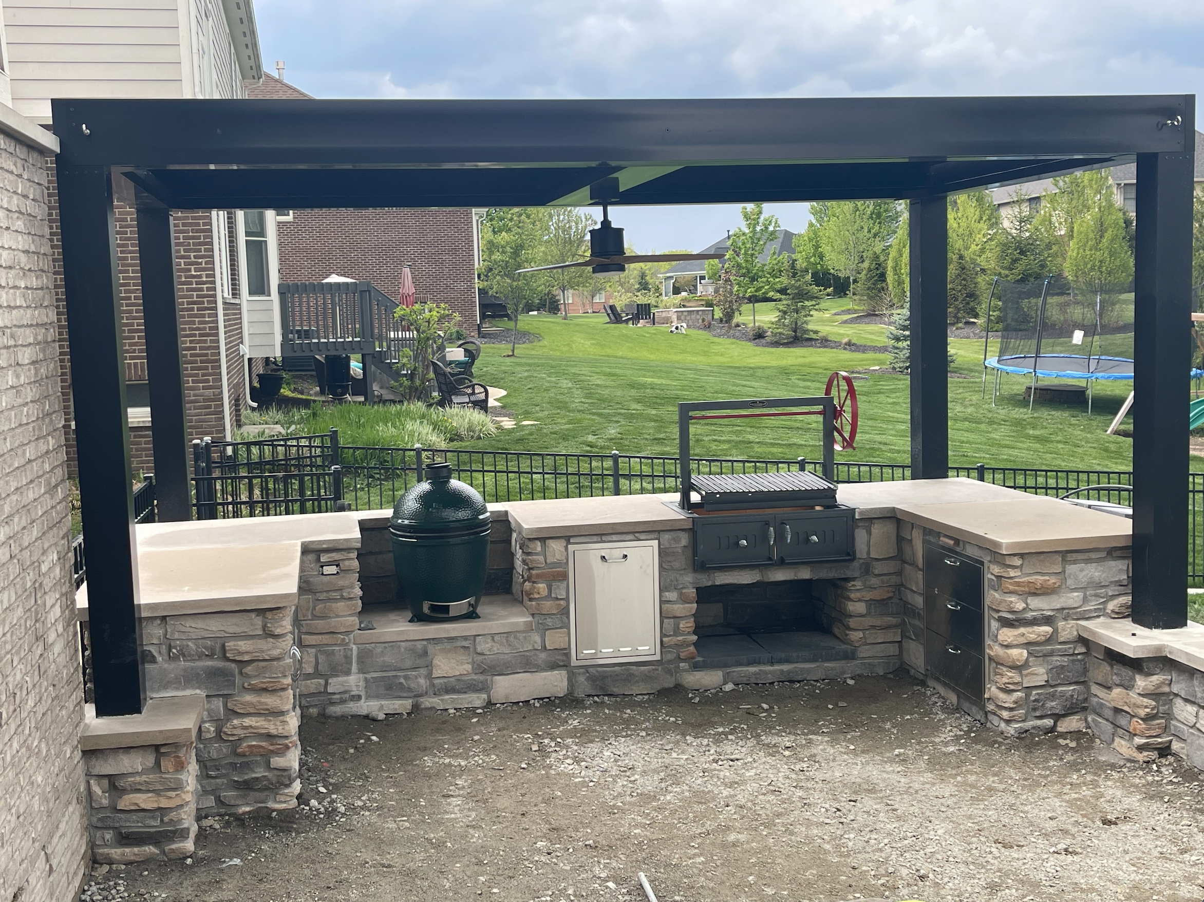 Outdoor Kitchen pergola ideas. Black structure in backyard. Matches house.