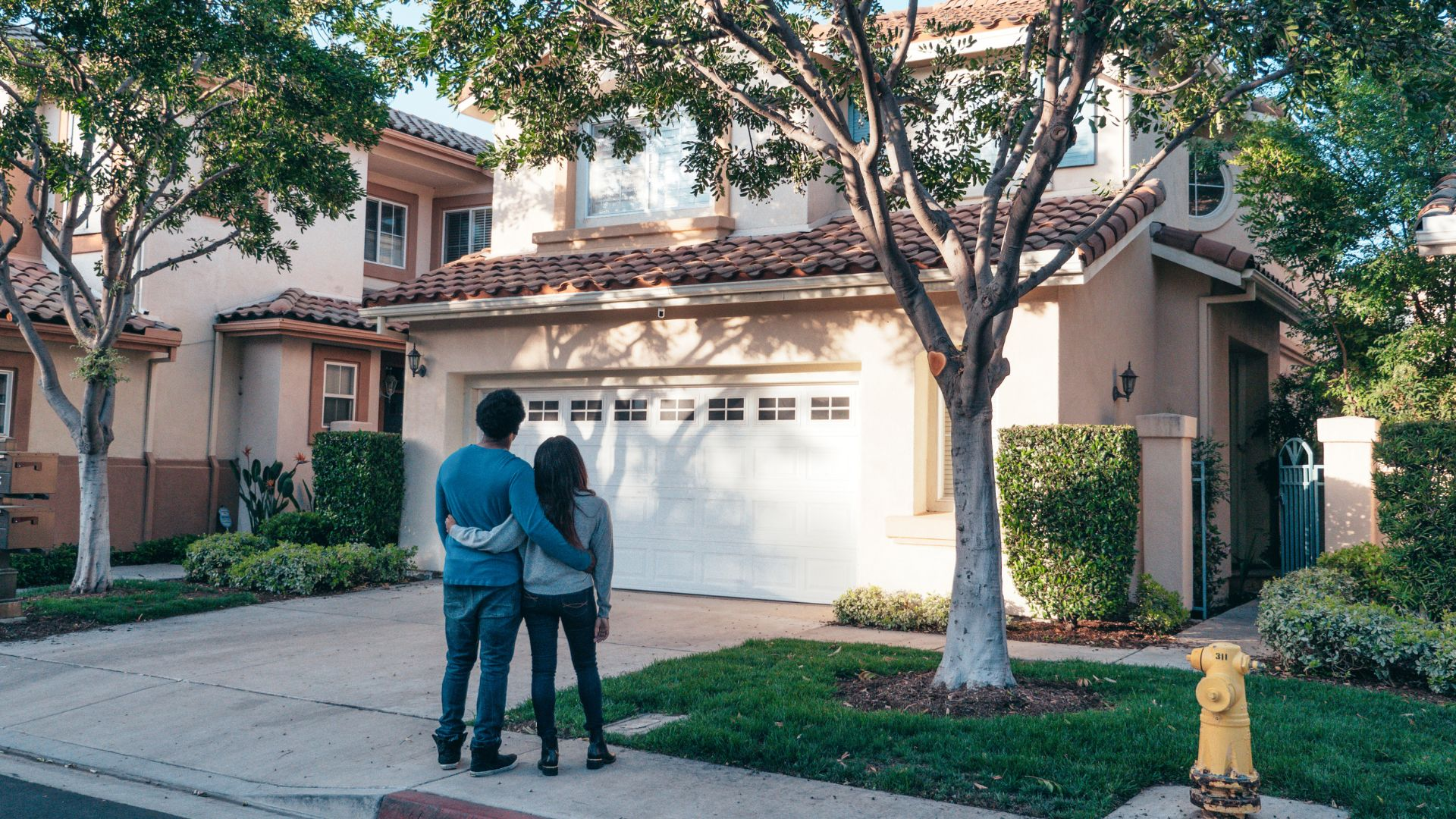 An image of homeowners looking on at their home in relief after using technology to prevent pests.