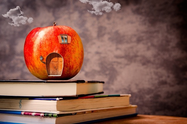An apple with a small door on a stack of books.