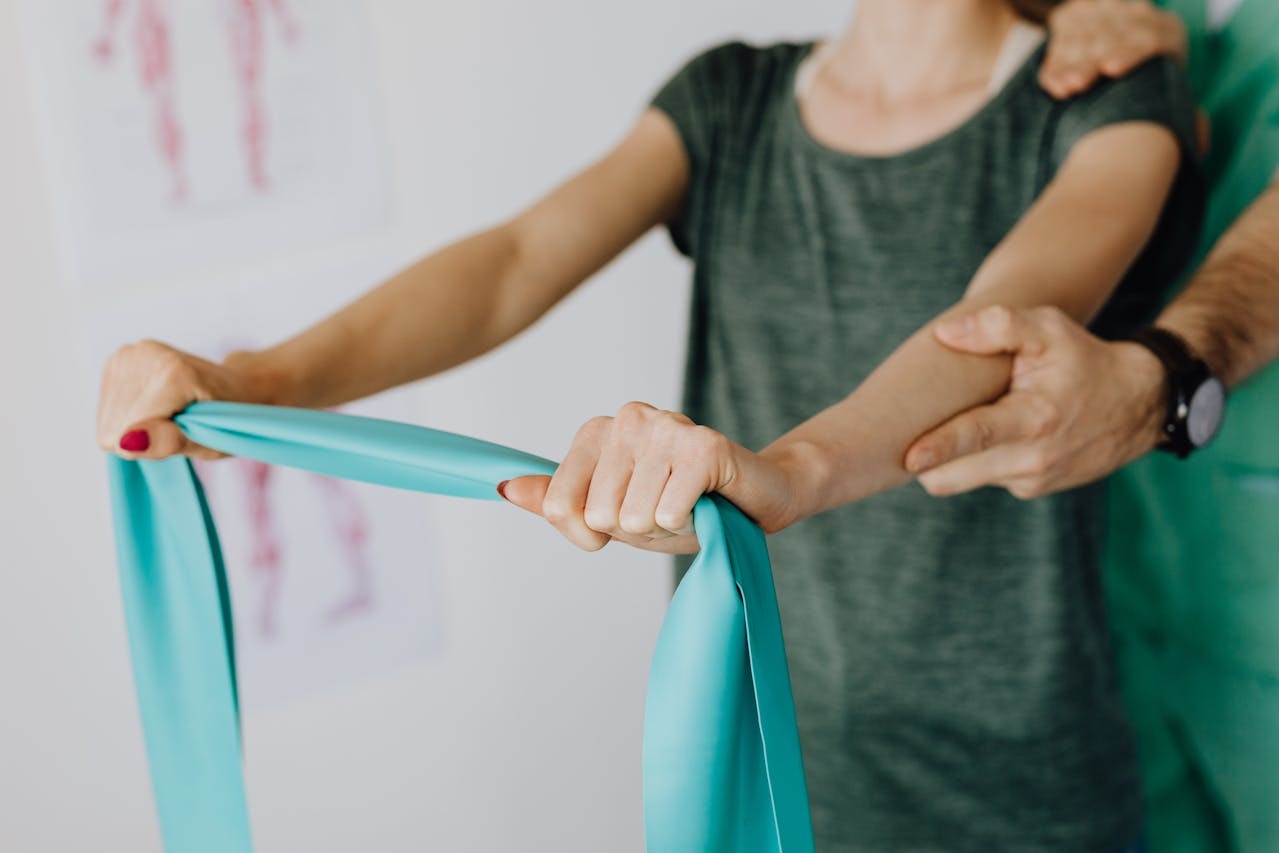 Physical therapist guiding a patient with a resistance band during upper body rehab exercise