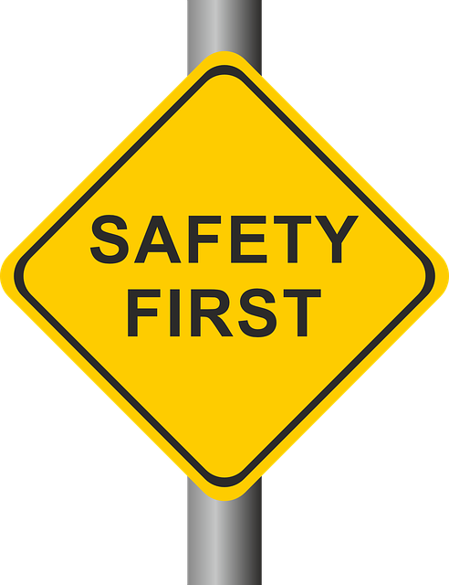 An image of a yellow sign on a pole, with black letters that read, safety first. 