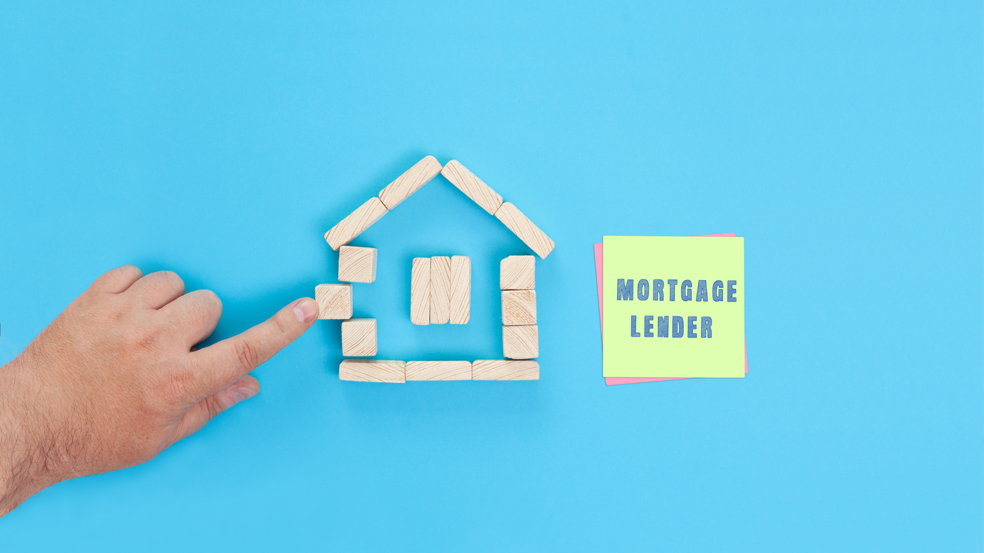 Understanding The Role of LMI In Property Investment - A Man Showing A House Built With Small Wooden Blocks and A Sticky Note Where its Written Mortgage Lender