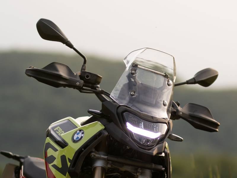 vista frontal de una moto BMW F 900 GS equipada con una pantalla transparente y protectores de manos