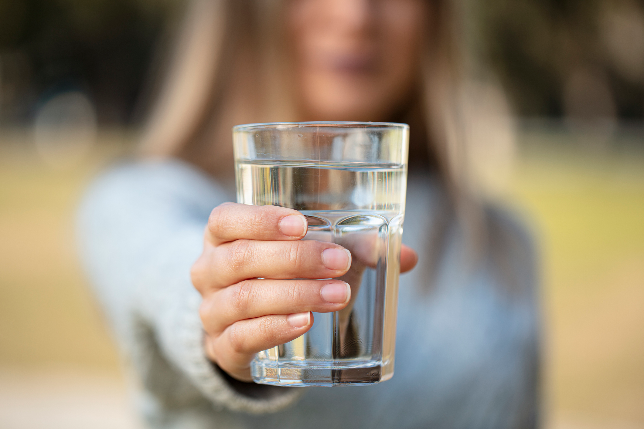 An image of a woman holding a glass of water, preparing to gargle.