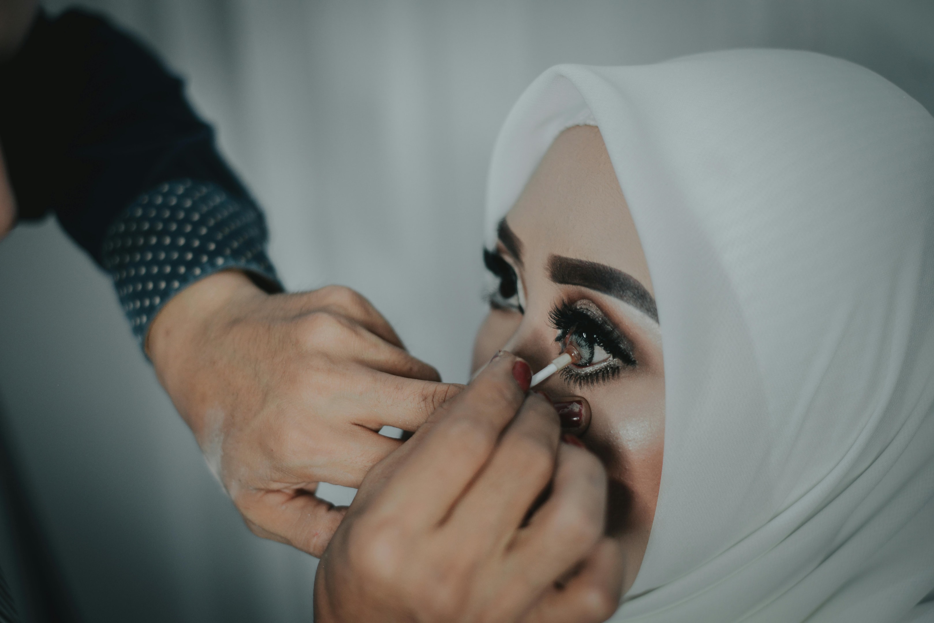 A hijabi getting a contact lens inserted by a professional