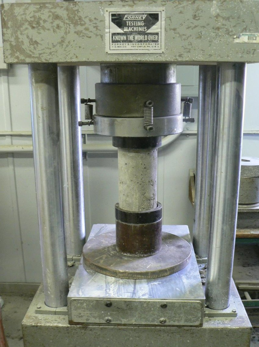 Concrete cylinder being tested for compressive strength according to ASTM C39