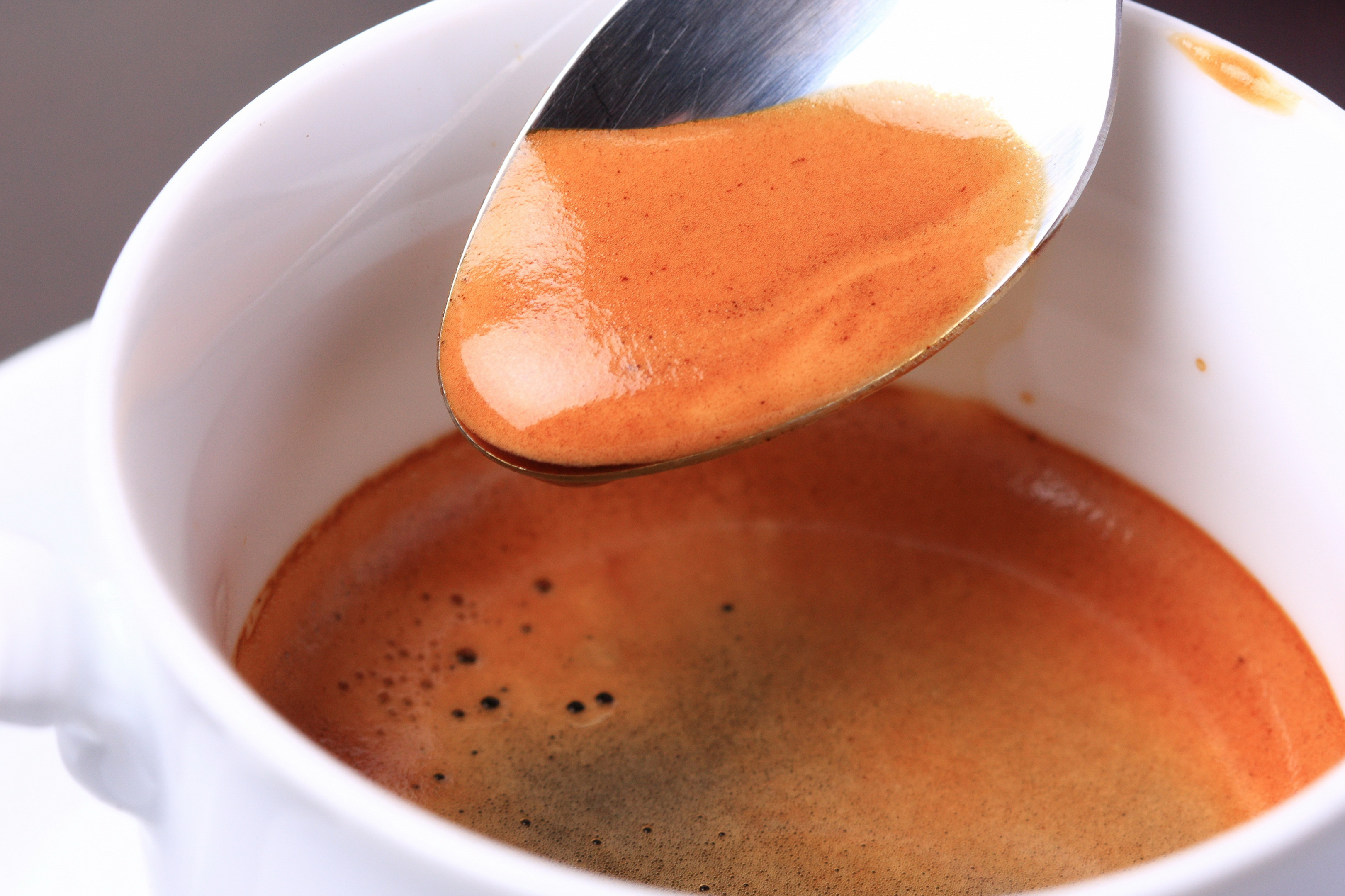 White espresso cup half full with spoon showing blonde espresso