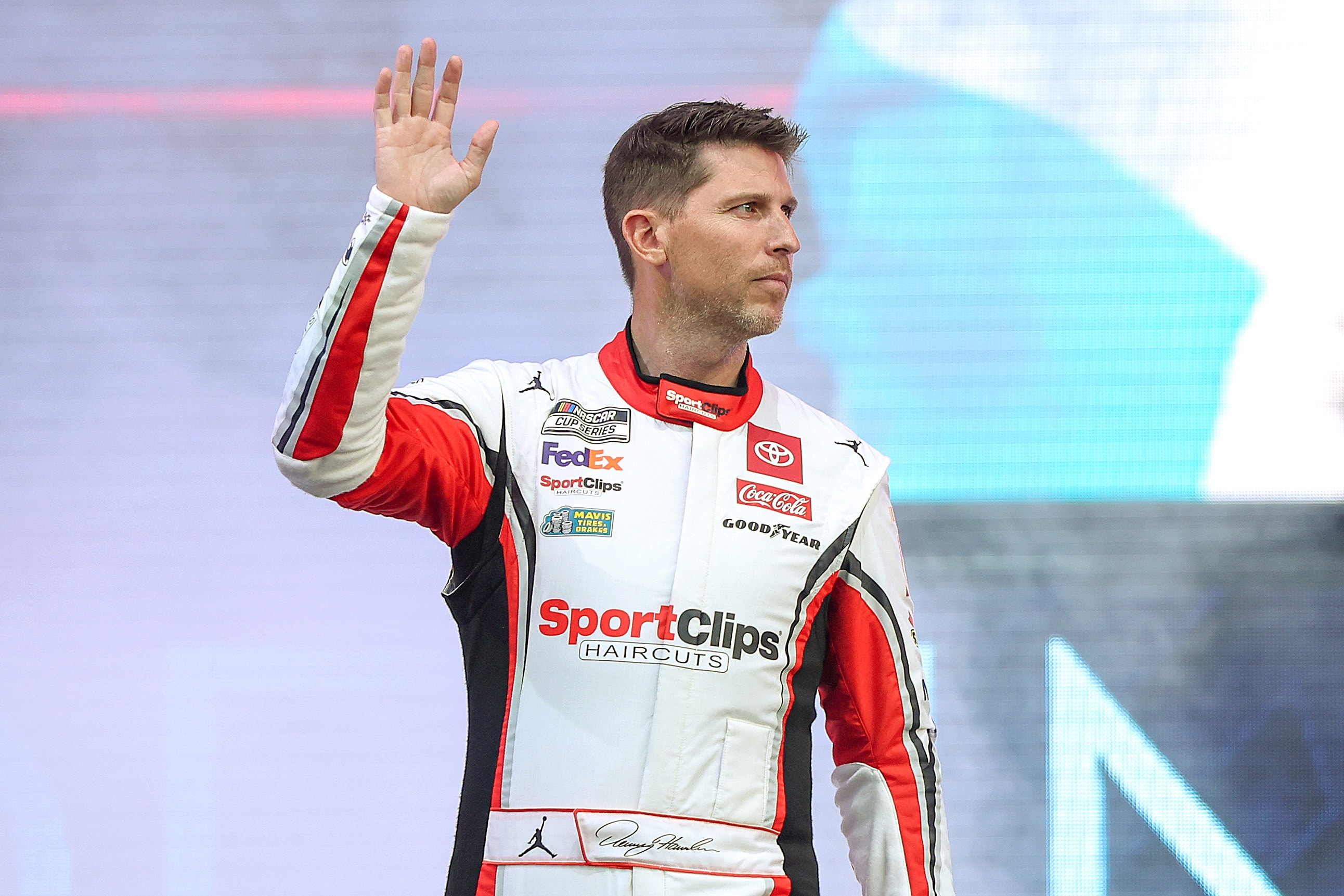 Denny Hamlin, driver of the #11 Sport Clips Haircuts Toyota, waves to fans as he walks onstage during the NCS Driver Engagement on the Main Stage at the Chicago Street Course on July 06, 2024 in Chicago, Illinois. 