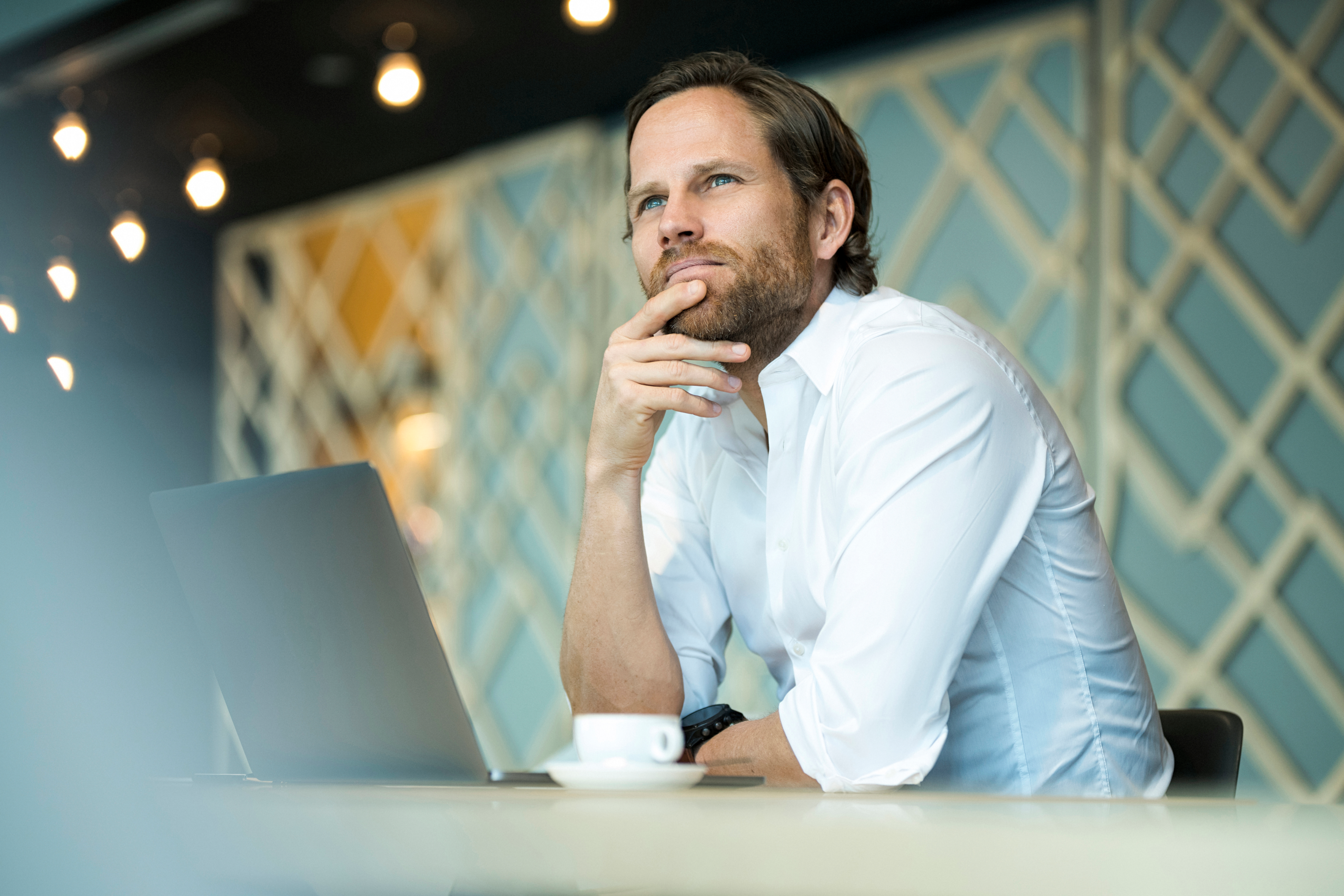 Business man thinking while using laptop