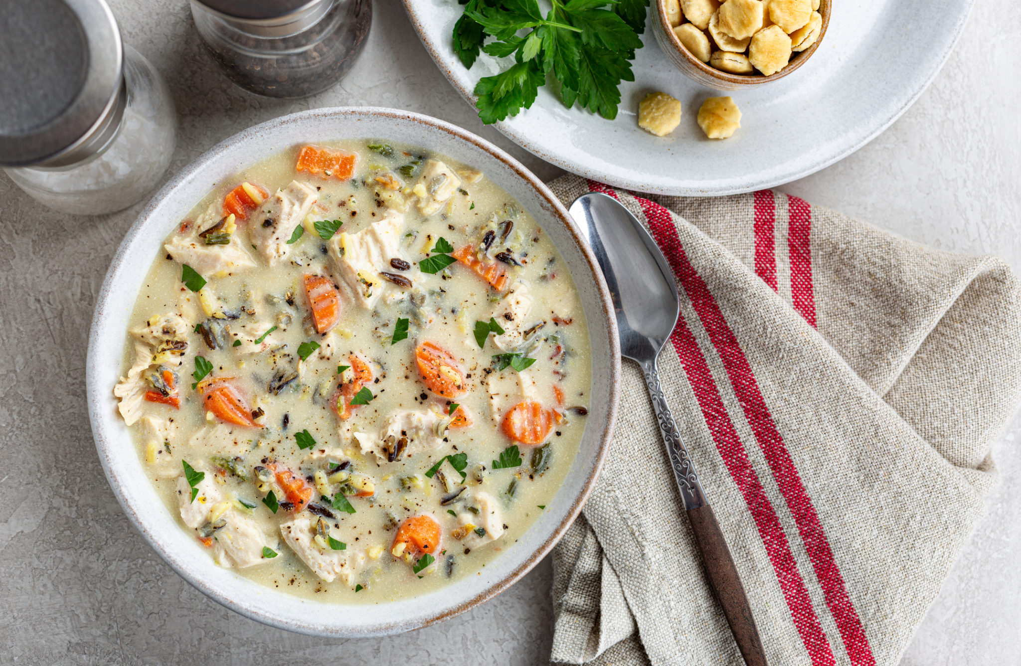 A bowl of keto chicken soup cooked in a crock pot with uncooked chicken, flavorful soup, and rice soup