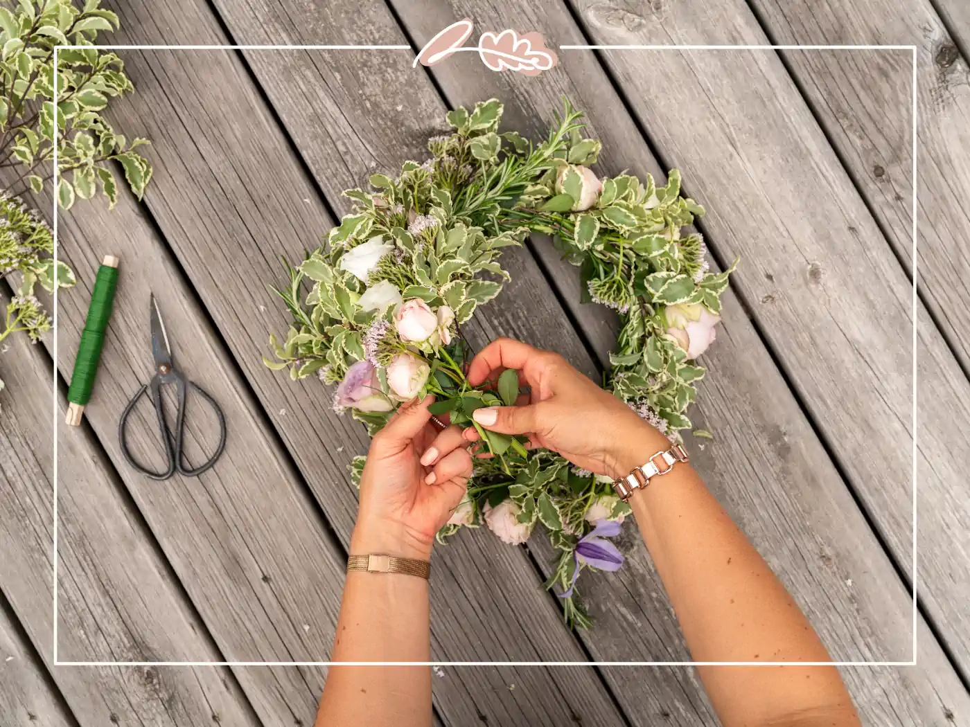 Hands creating a lush greenery and pastel floral crown on a wooden table. Enchanted Garden Floral Crown by Fabulous Flowers and Gifts.