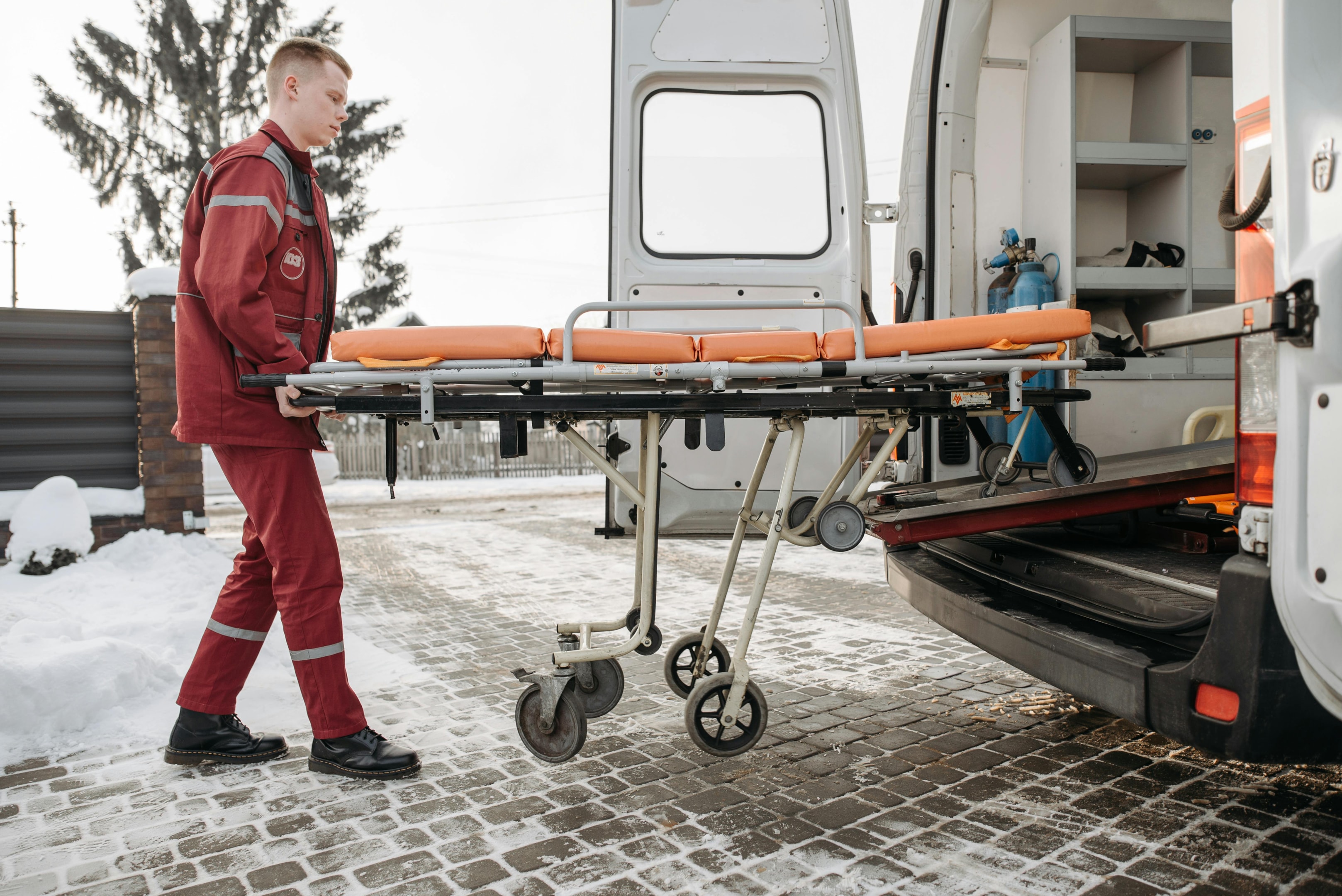 Paramedic loading a stretcher into an ambulance