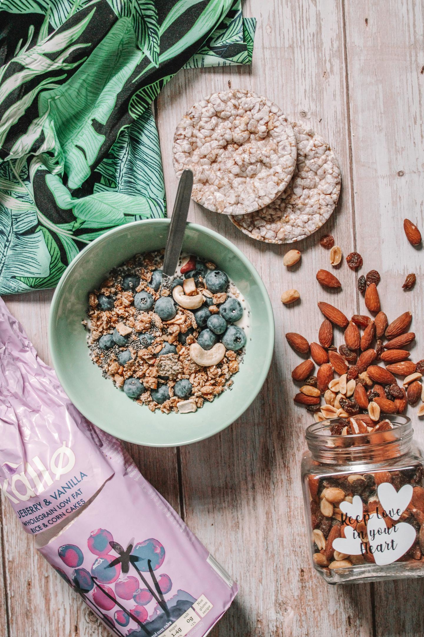 A bowl of gronola with nuts, rice cakes, and blueberries.