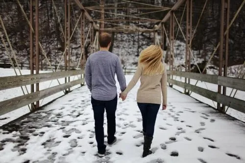 couple walking through the snow on a bridge at one of the best places to visit in ct during winter vacation getaways