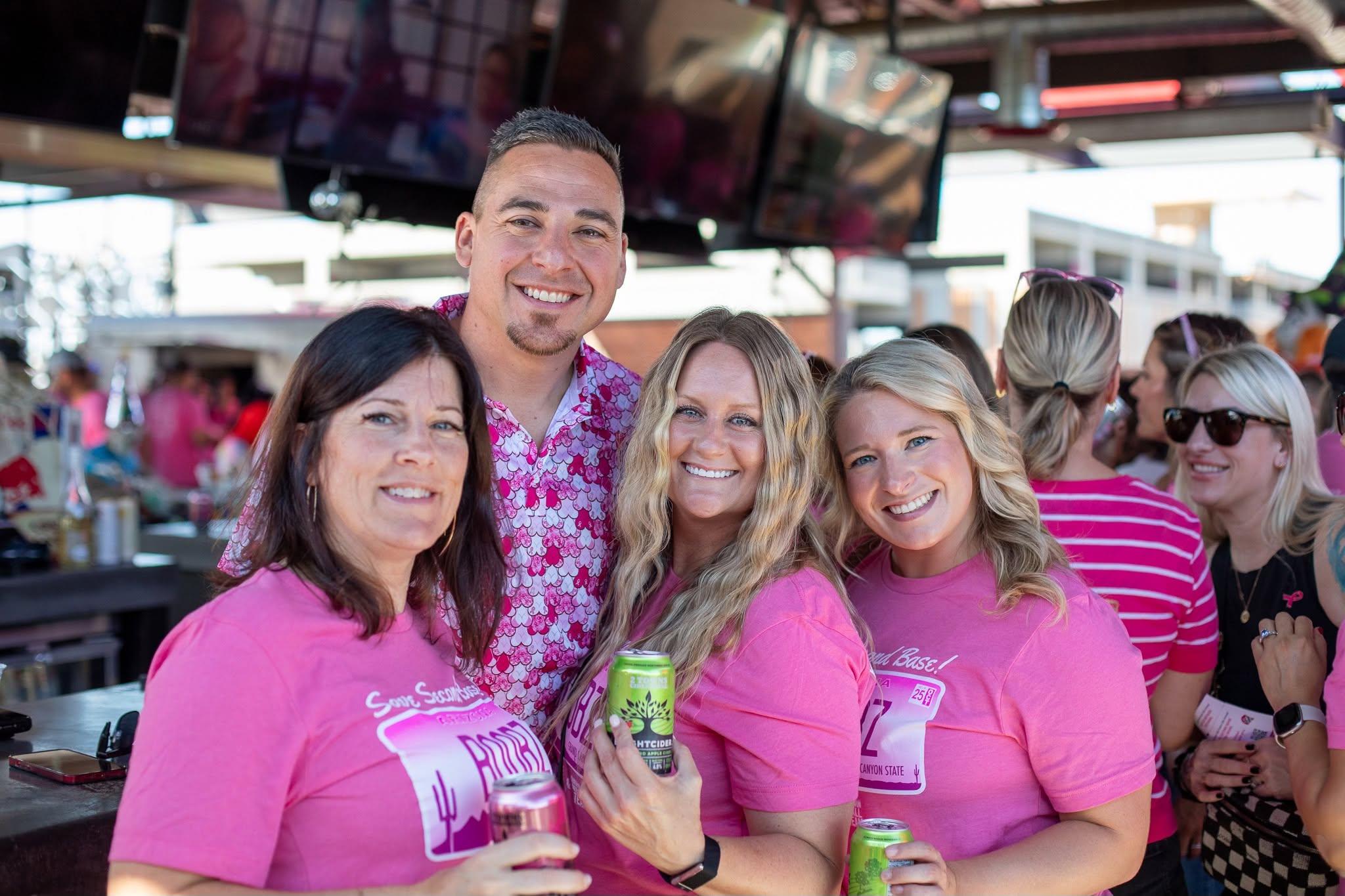 Friends in pink shirts celebrating at the Save Second Base Pub Crawl in Downtown Chandler, Arizona
