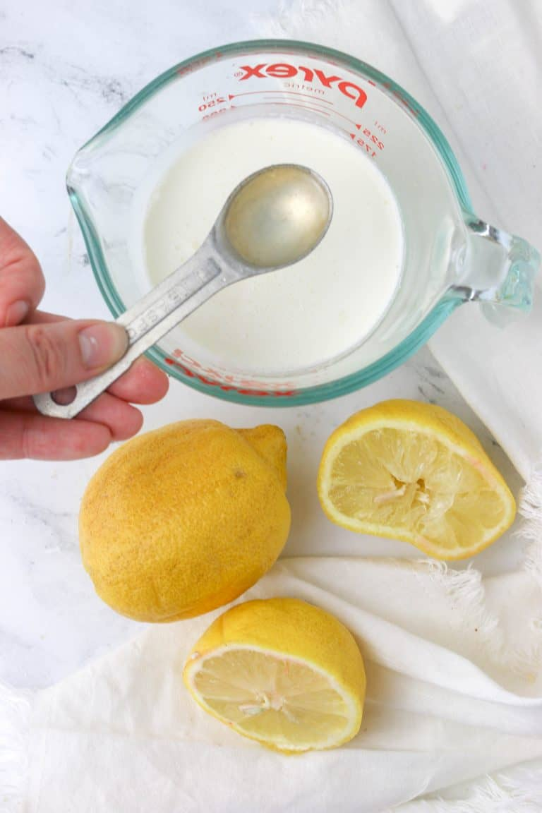 lemons and glass measuring cup of milk with lemon juice being added to make homemade buttermilk