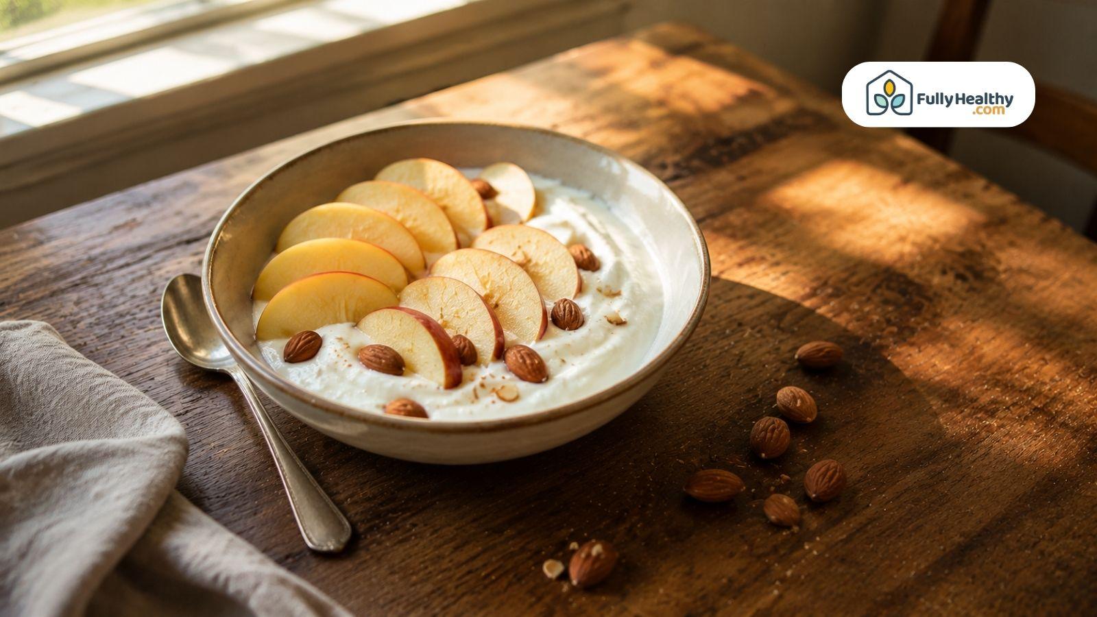 Healthy breakfast bowl with yogurt, apples, and almonds in sunlight.