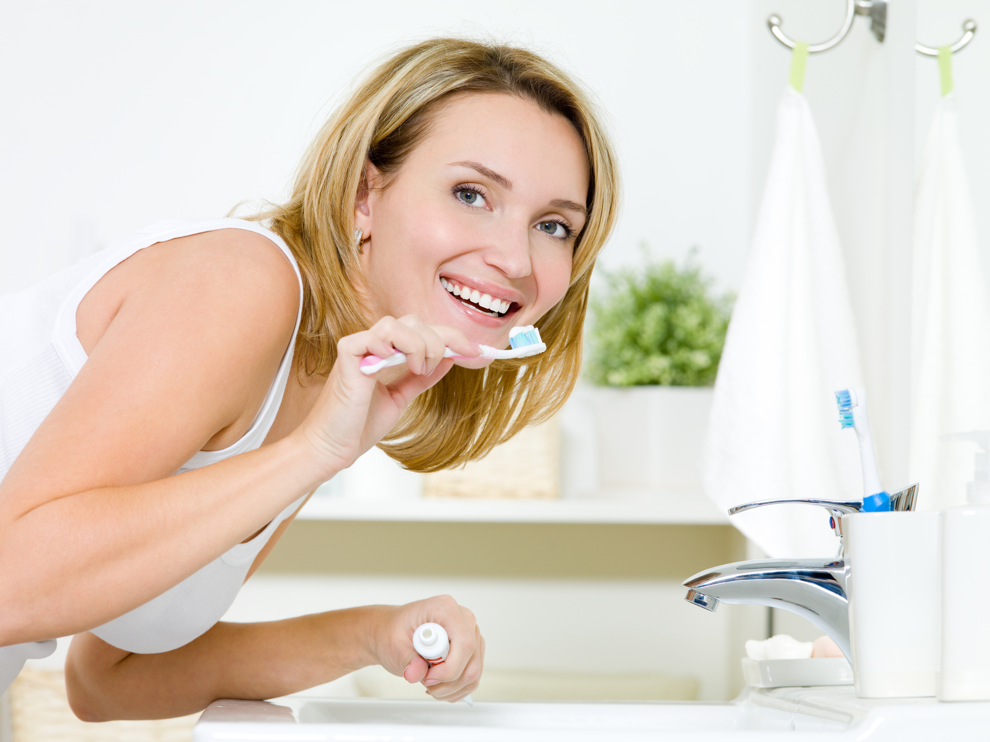 A woman brushing her teeth and calgary dental implants