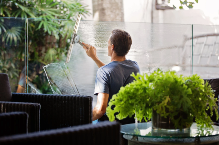 man cleaning clear glass wall