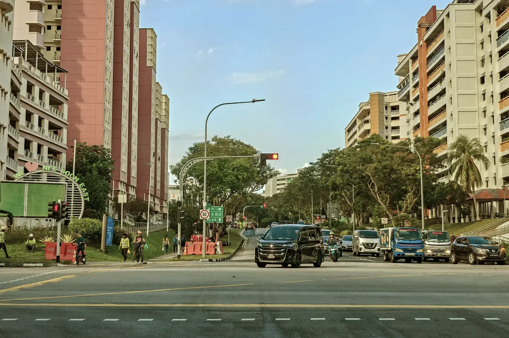 Cars stopped at intersection with HDB flats in background.