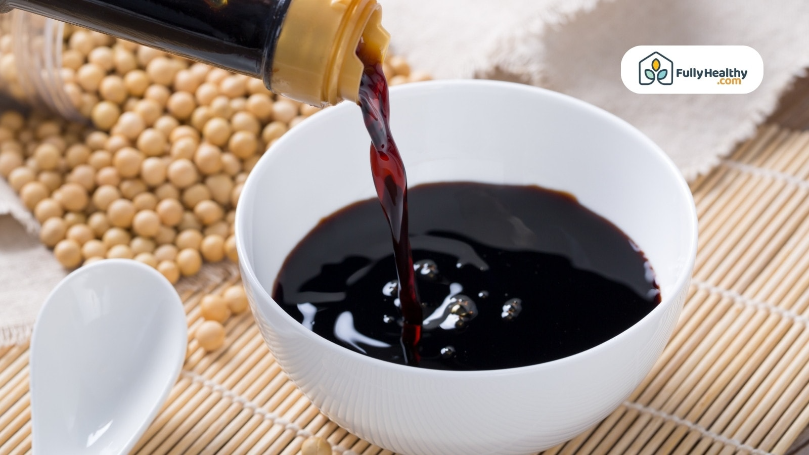 Dark soy sauce pouring into white bowl with soybeans background