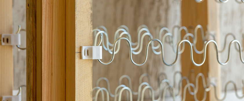 A close up of a sinuous/zig zag spring system in a wooden frame.