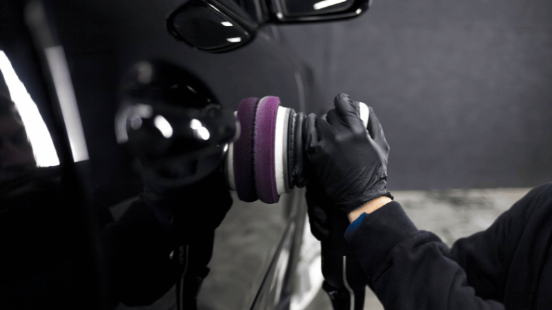 A man is correcting the car's minor scratches.