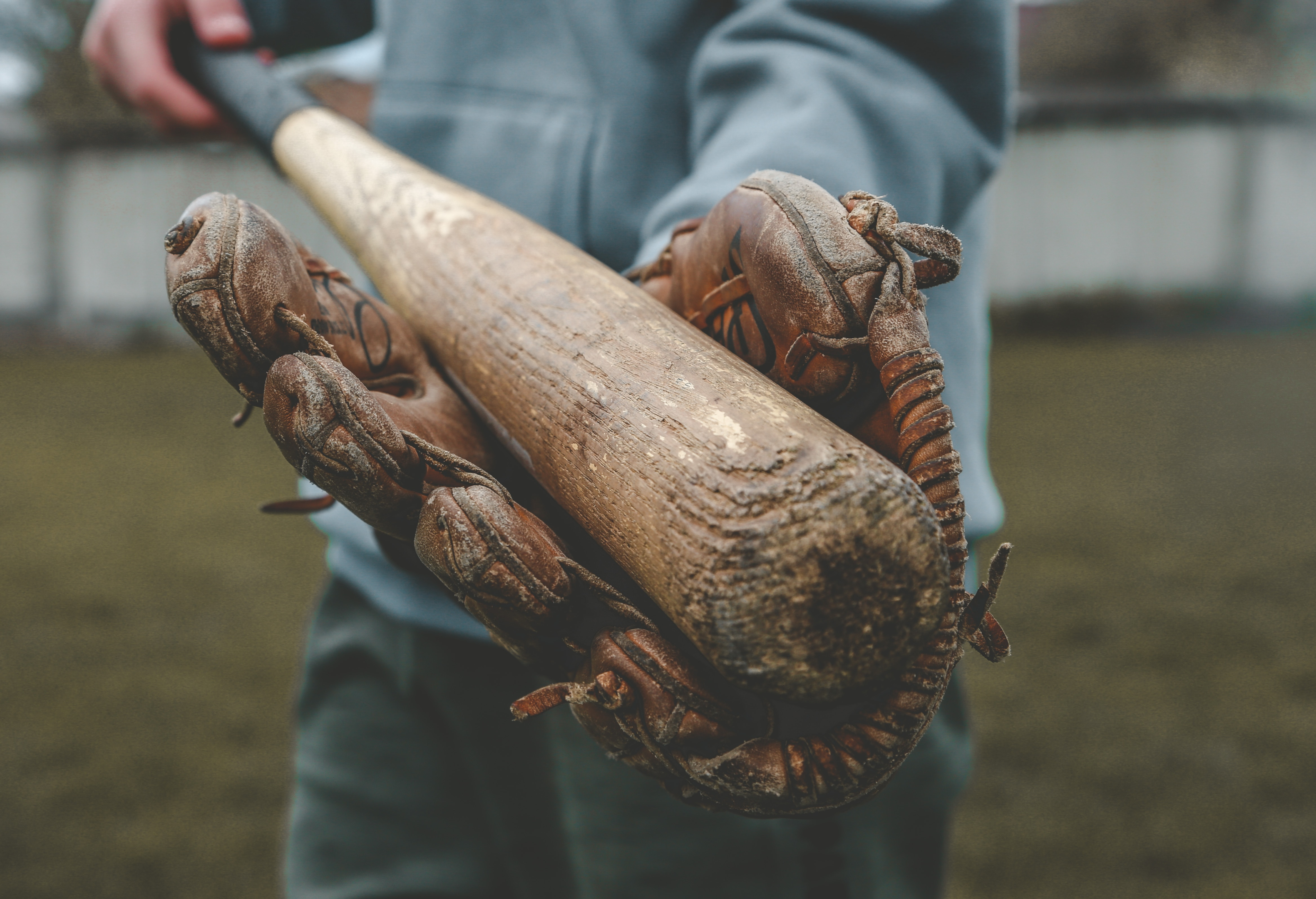 A player holding a worn out woodn baseball bat.