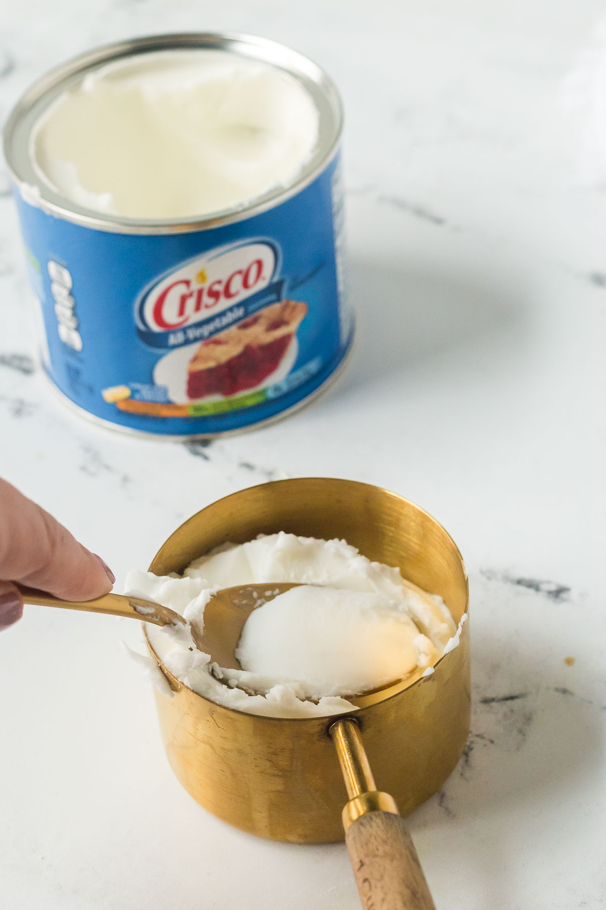 spoon pressing shortening into a measuring cup