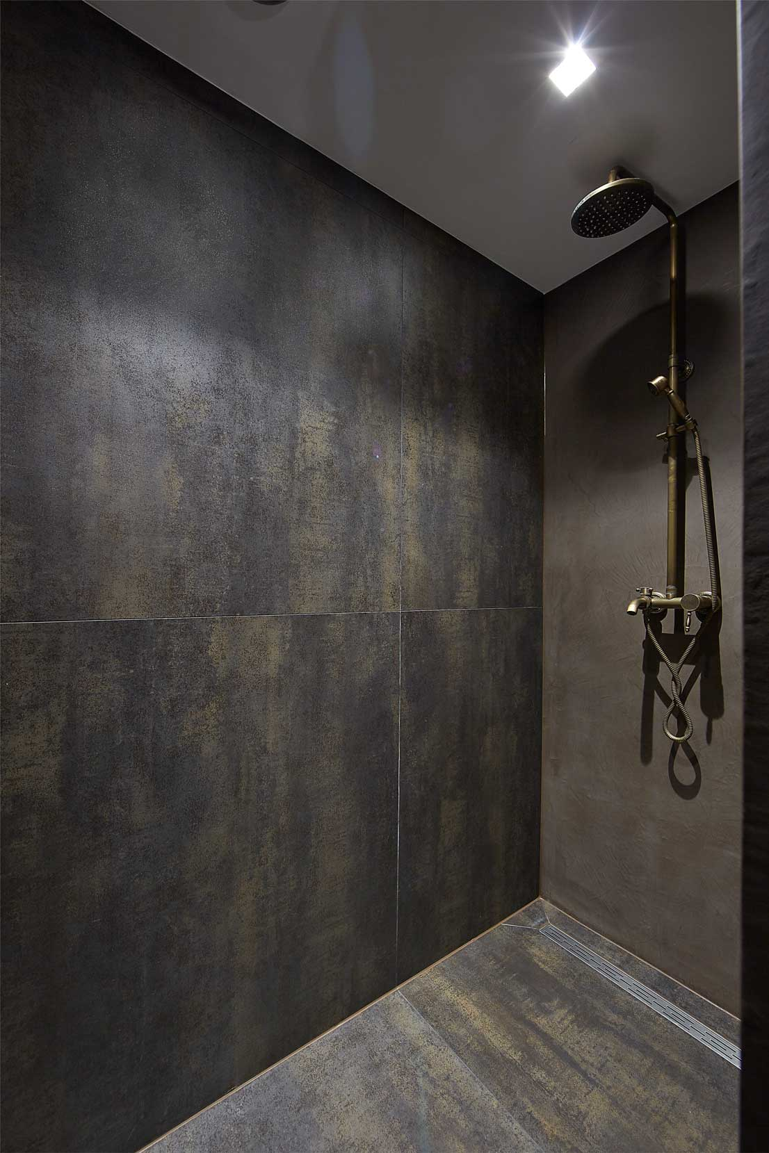 Custom-made shower with dark tiles installed on the wall