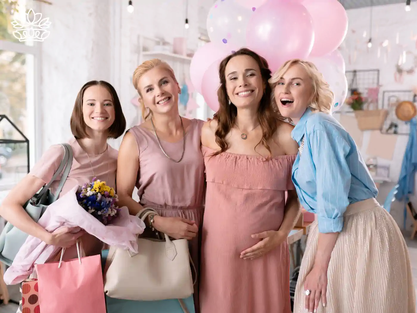 Four women smiling and posing at a baby shower, holding gifts and flowers, with pink balloons in the background. Fabulous Flowers and Gifts: Baby Shower Flowers Collection