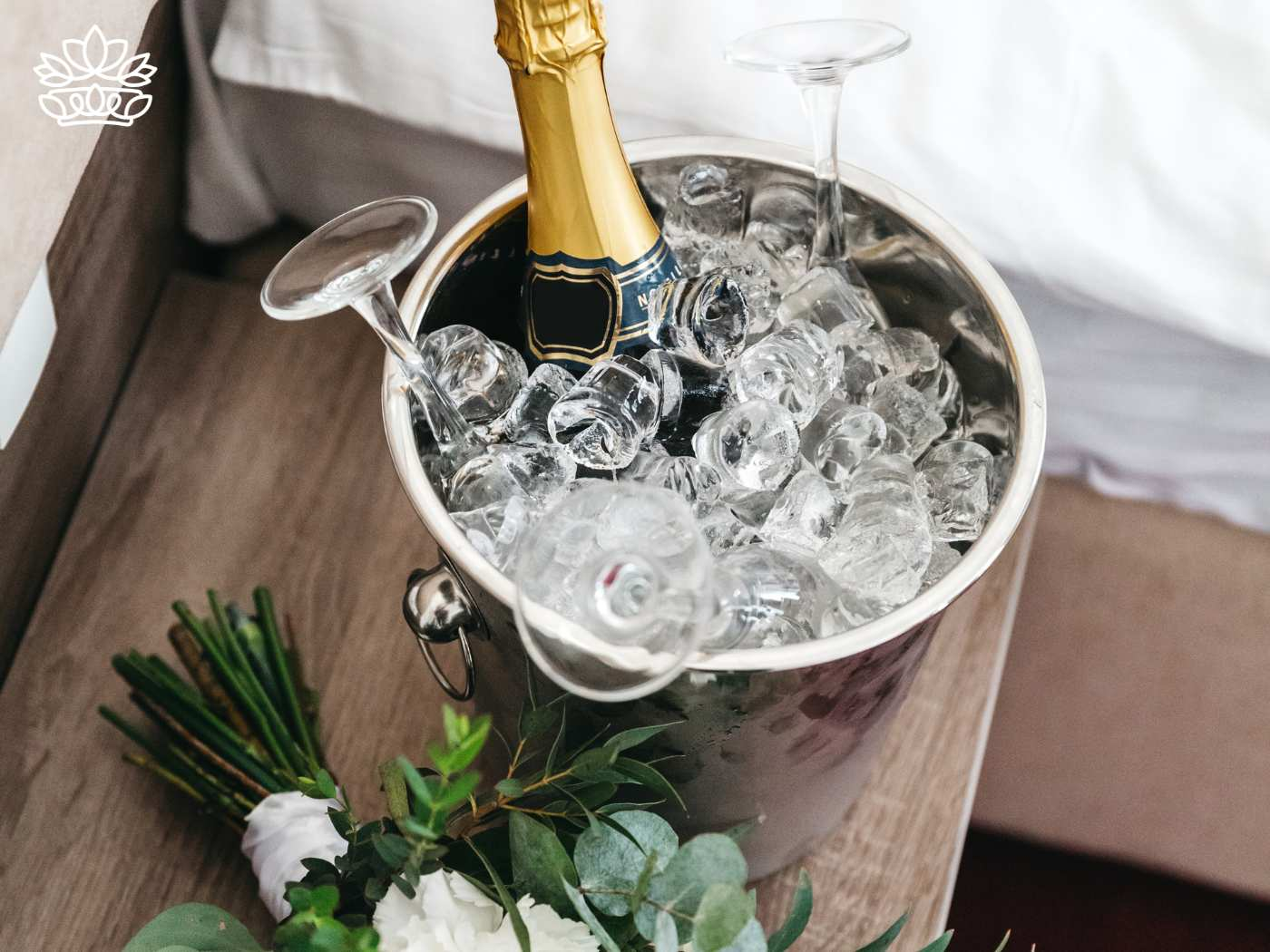 A champagne bottle and glasses in an ice bucket, next to a bouquet of flowers. Flowers with Champagne & Wine. Delivered with Heart. Fabulous Flowers and Gifts.