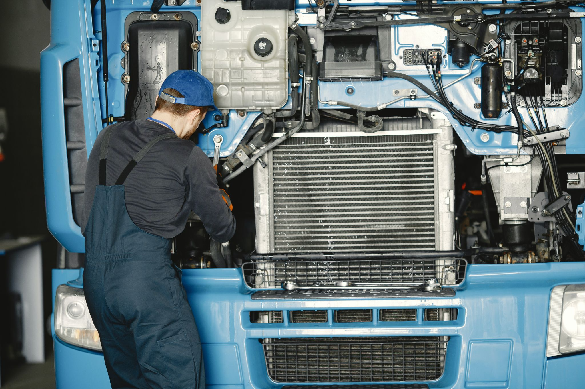 A mechanic working on a blue truck, their back facing the camera