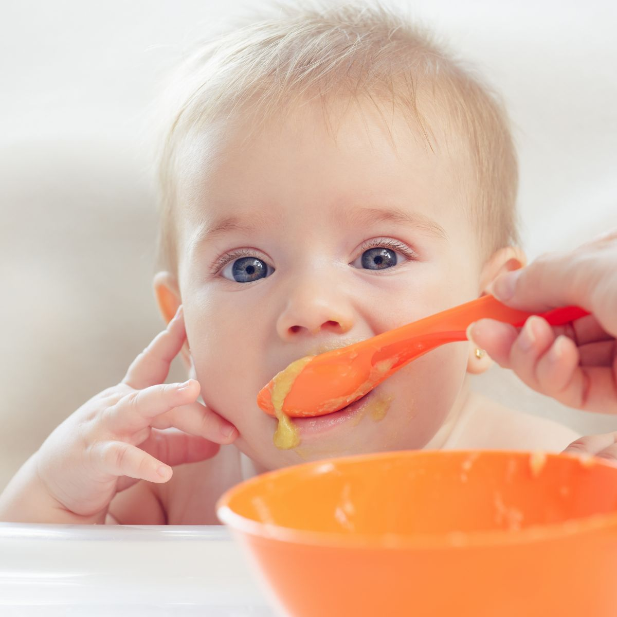 Baby eating out of orange spoon