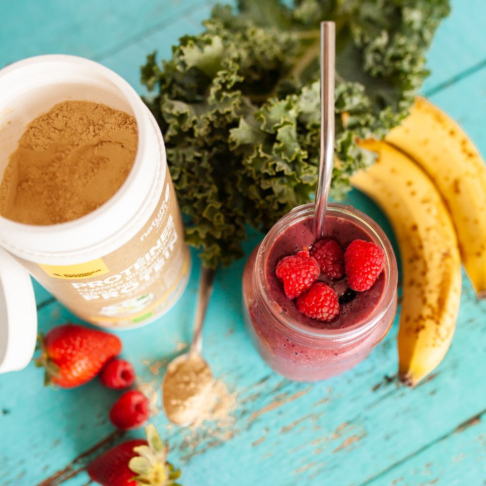 A glass of protein shake with a scoop of protein powder on the side