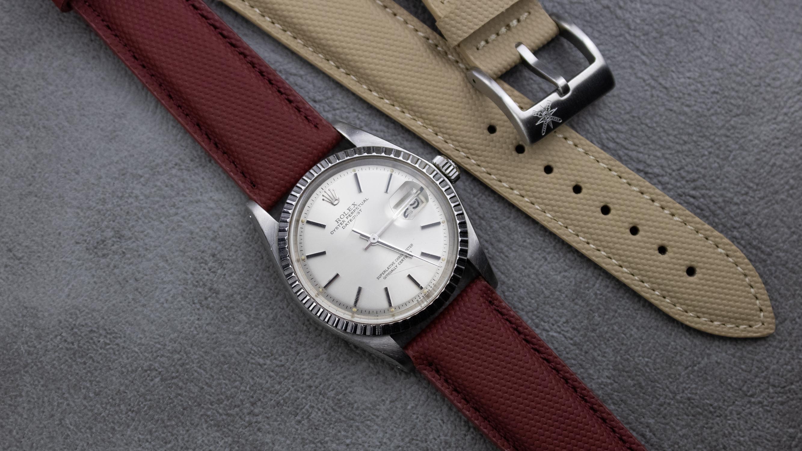 A close-up of a burgundy red sailcloth watch strap, showcasing its texture and design.