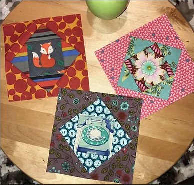 Three economy blocks with fussy cut centres on a wood table. A free pattern and tutorial by Just Get It Done Quilts. 