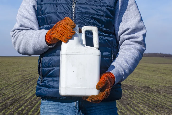 A person holding a herbicide container