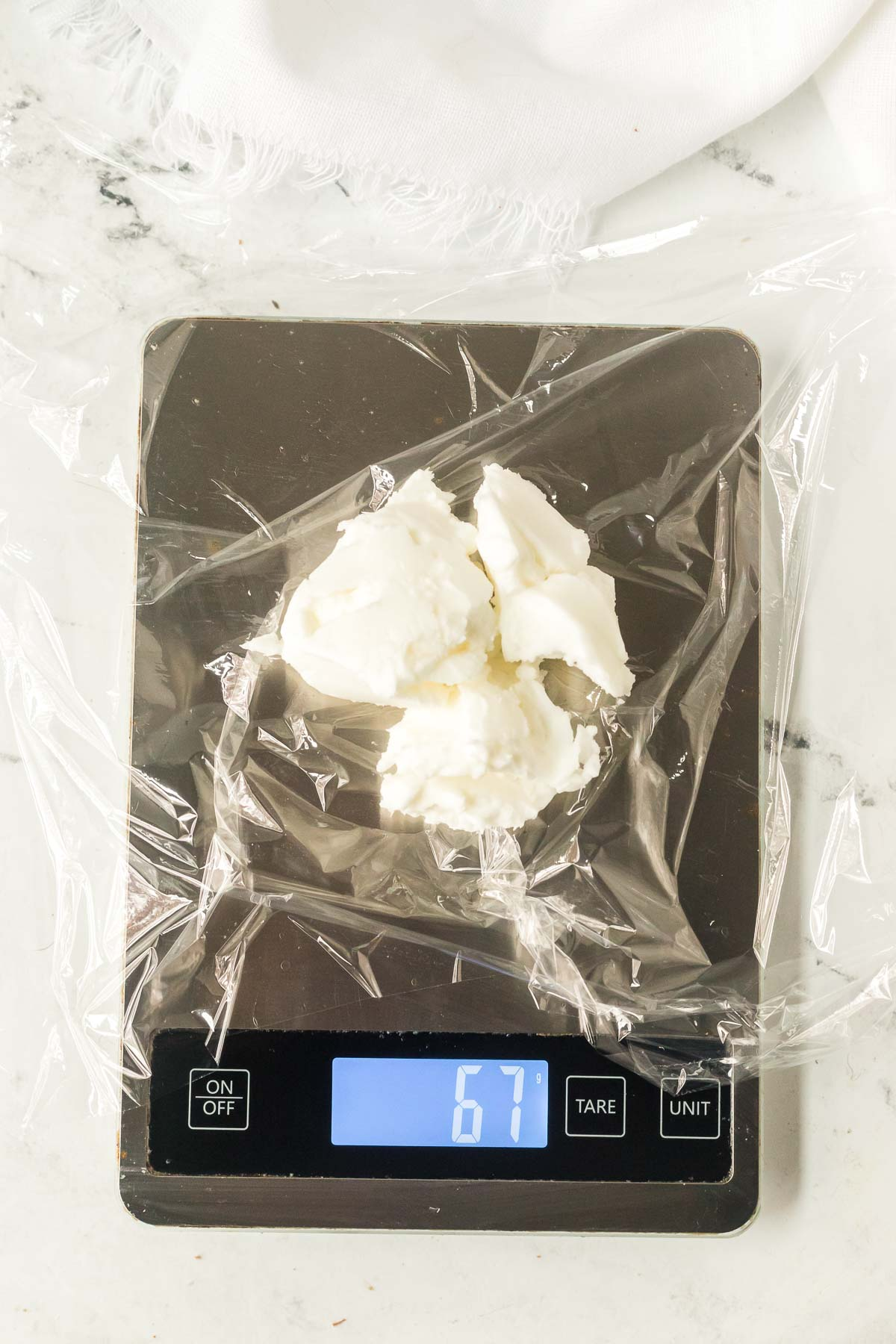 a kitchen scale with plastic wrap on top and shortening measured out onto it