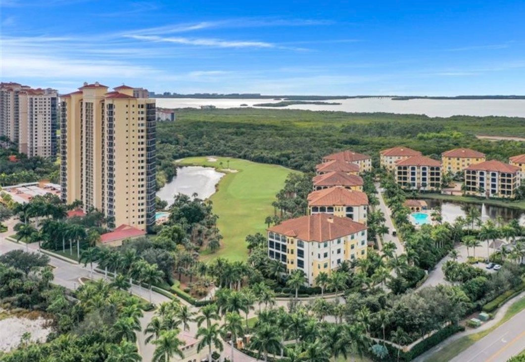 An aerial view of The Colony at Pelican Landing showcases its stunning waterfront location and championship golf course, highlighting the elevated coastal living experience offered by this exclusive community in Bonita Springs, FL. The image captures the expansive layout of the community, featuring world-class amenities and breathtaking panoramic views.