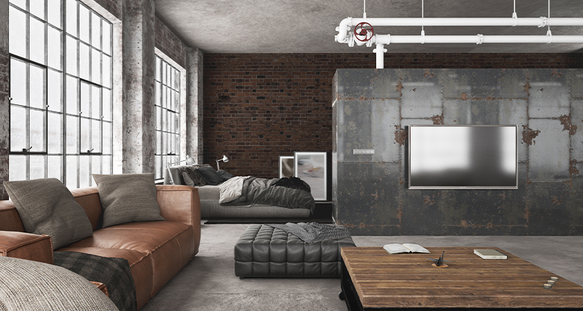 This room features an exposed brick wall, wide windows with a metal frame, a large glossy stone dividing wall and white pipes suspended from the ceiling. 